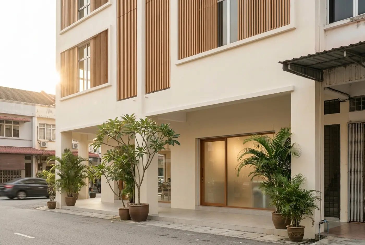 The Serene Moon building: two linked cream shop-lots with timber screens and potted frangipani in Bandar Puteri